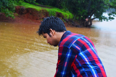 Man standing by lake against tree