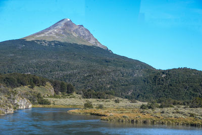 Scenic view of lake and mountains against clear blue sky