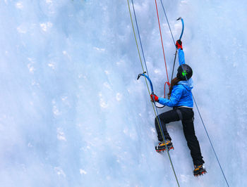 Rear view full length of woman ice climbing