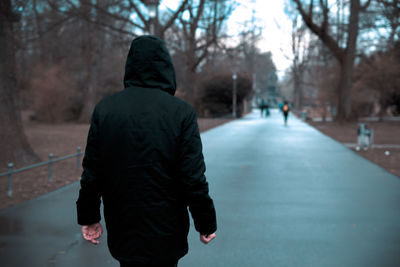 Rear view of man walking on footpath