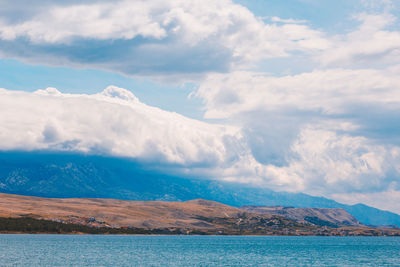 Scenic view of sea by mountains against sky