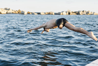 Man surfing in sea against sky