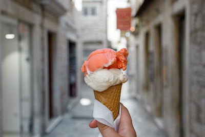 Personal perspective of female hand holding delicious colorful ice cream in cone in street