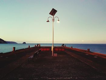 Road sign by sea against clear sky