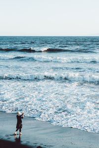 High angle view of woman standing at beach against clear sky