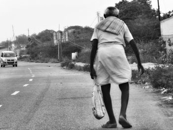 Rear view of a woman standing on road