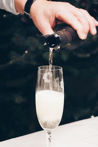 Cropped hand pouring champagne in flute from bottle