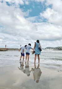 Rear view of people walking on beach under a storm 