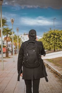 Rear view of man walking on footpath against sky