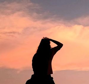 Silhouette woman standing against orange sky