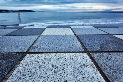 Surface level of footpath by sea against sky