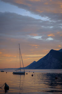 Sailboats in sea against sky during sunset