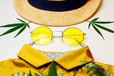 Yellow sunglasses, hat, marijuana leaves, yellow shirt - assembled in the form of a portrait of 