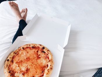 Low section of woman with pizza on bed