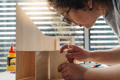 Side view of young woman making model home on table