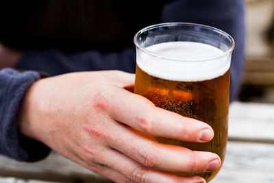 Cropped image of hand holding beer glass