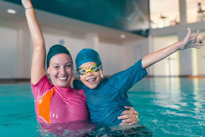 Portrait of cheerful with teacher in swimming pool