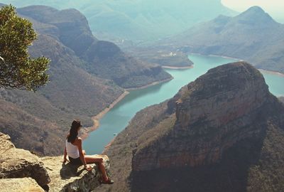 Woman sitting on rock against mountains