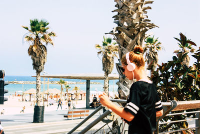 Woman standing by palm trees against clear sky