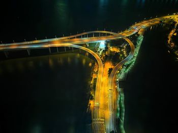 Light trails on bridge against sky at night