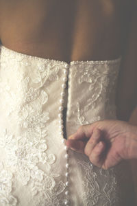 Cropped hand of bridesmaid adjusting bride dress