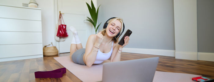 Portrait of young woman using mobile phone while sitting at home