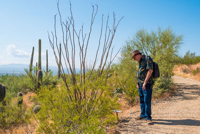 Side view of man standing on land against sky