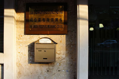 Mailbox mounted below information sign on wall