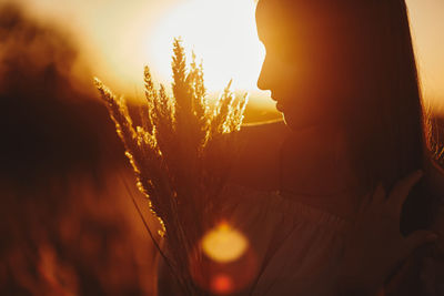 Close-up portrait of woman against orange sunset sky