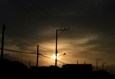 Low angle view of silhouette electricity pylon against sky