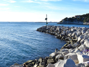 Scenic view of rocky beach against cloudy sky