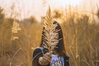 Young woman holding plant against face