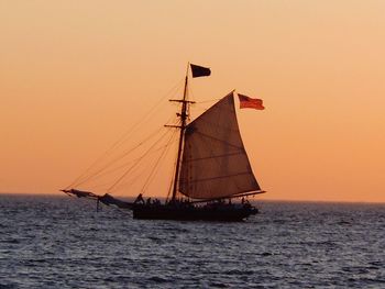 Sailboat sailing in sea at sunset