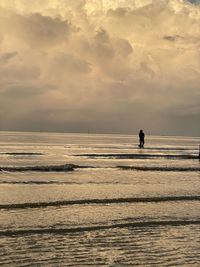 Silhouette person on beach against sky during sunset