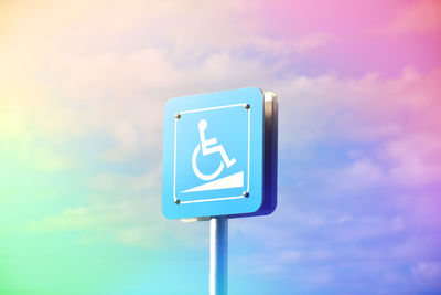 Low angle view of wheelchair sign against sky