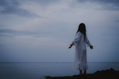 Rear view of woman standing against sea