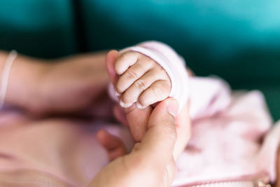 Close-up of person holding baby hand