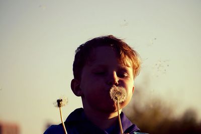 Portrait of boy blowing dandelion