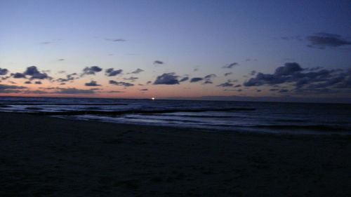 Scenic view of beach against sky at dusk