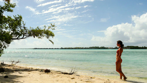 Woman standing at beach against sky