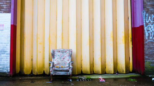 Abandoned armchair against wall