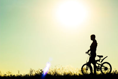 Silhouette woman with bicycle against sky during sunset