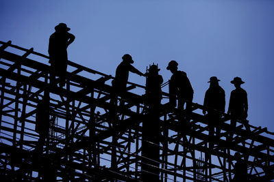 Low angle view of silhouette people standing against sky