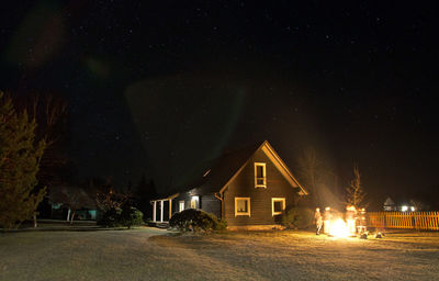 Illuminated houses against sky at night