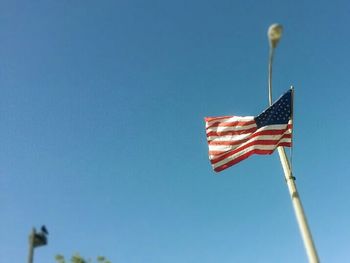Low angle view of american flag against clear blue sky