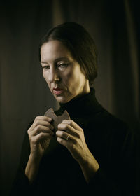 Woman dressed in black with chocolate in her hand in a romantic attitude iii