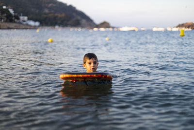 Boy looking away while surfing on sea