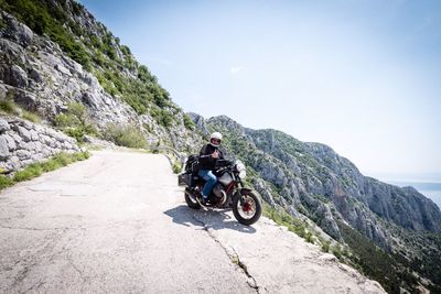 Man riding bicycle on mountain against sky