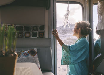 Side view of woman by doorway of camping van