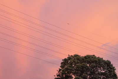Low angle view of power lines against sky at sunset